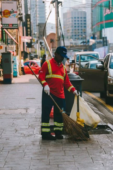 services-02 Osoba u zaštitnom odijelu dezinfikuje bijeli sto u zatvorenom prostoru pomoću raspršivača.
